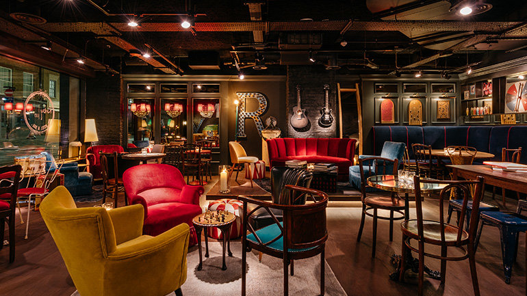 Image of Ruby Lucy Hotel & Bar, London, England showcasing the bar. The bar is a retro style with a variety of colours. The walls feature guitars and artwork to give an alternative diner feeling.
