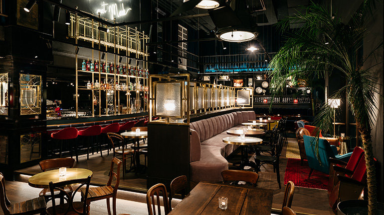 Image of Ruby Mimi Hotel & Bar, Zurich, Switzerland showcasing the bar. The bar is classic and features neon lighting, gold trimmed mirrors and booth seating.