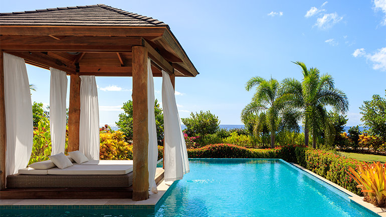 Ocean view of private, poolside cabana at InterContinental Dominica Cabrits Resort & Spa, showcasing lush, tropical plants and sunny blue skies