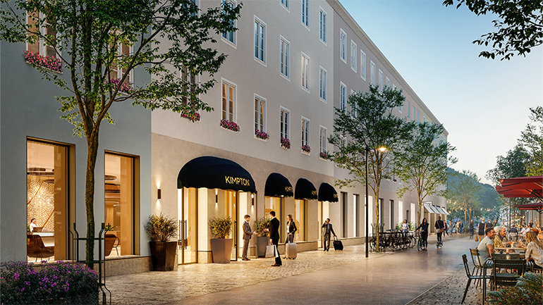 Exterior view of Kimpton hotel with black awnings, large windows, and people walking along a tree-lined street with outdoor café seating.