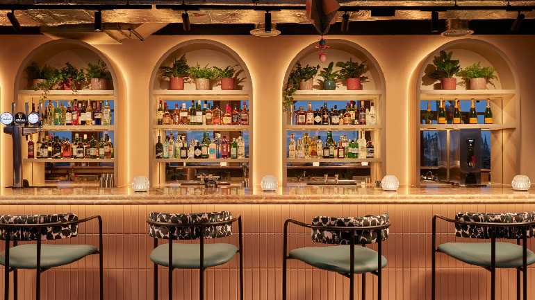 Hotel Indigo Gloucester - The Forum Stylish hotel bar with illuminated shelves, bottles and high stools.