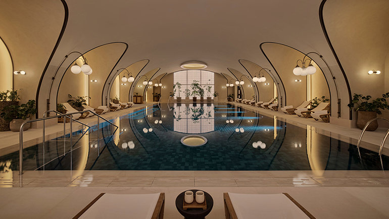 Indoor swimming pool with arched ceilings, curved lighting features, poolside loungers and a calm, spa like atmosphere.