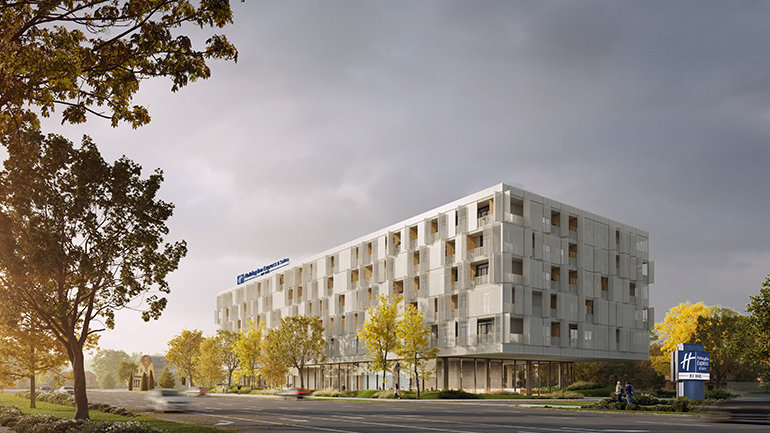 Architectural rendering of a modern Holiday Inn Express & Suites hotel. The six-storey building features a contemporary white façade with geometric detailing, large windows and ground-floor glazing. The hotel sits along a tree-lined road with landscaped gardens and a freestanding Holiday Inn Express by IHG sign visible at the entrance.