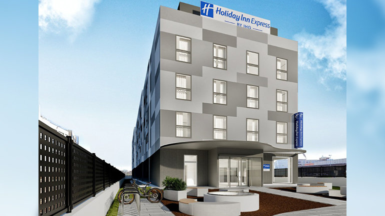 Design rendering of the Holiday Inn Express Barcelona Fira exterior, showing a modern mid-rise building with a geometric façade, branded signage, and a landscaped entrance with seating and bicycle parking.